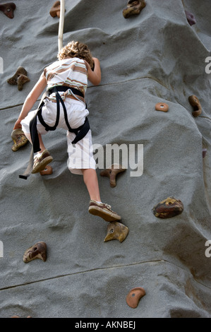 Jeune garçon escalade un mur de roche modèle portant un harnais de sécurité prises en mode portrait avec copie espace au bas Banque D'Images