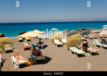 Les gens à bronzer sur les transats à la plage principale de la ville de Rhodes, Rhodes, Grèce Banque D'Images