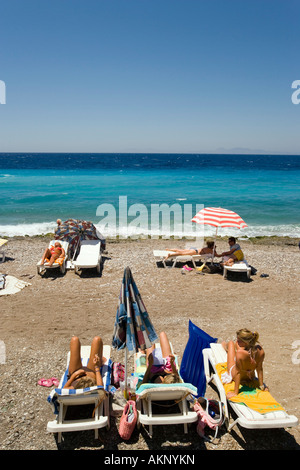 Les gens à bronzer sur les transats à la plage principale de la ville de Rhodes, Rhodes, Grèce Banque D'Images