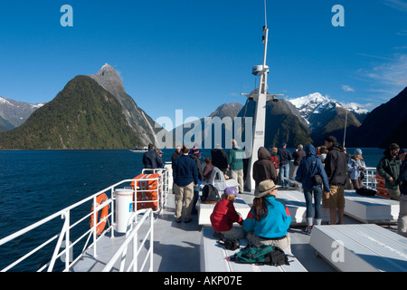 Les touristes sur le pont d'un bateau de croisière avec Mitre Peak derrière, Milford Sound, Fiordland National Park, South Island, New Zealand Banque D'Images