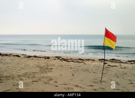 Drapeau de sécurité sur la plage dans le sable Praa Sands Cornwall UK nuageux jour mer plate Banque D'Images