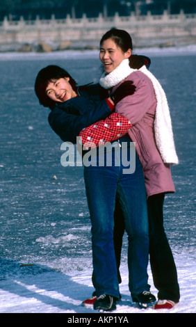 Enseignement fille ami à patiner sur le lac gelé au parc Beihai, Beijing Banque D'Images