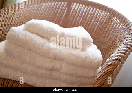 Pile de serviettes sur une chaise en osier dans la salle de bains Banque D'Images