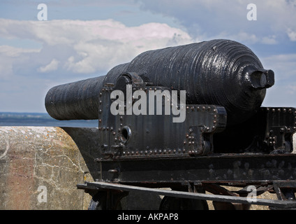 Canon noir en fer victorien sur le chariot pointant sur le mur et sortie en mer depuis les remparts de pierre sur l'île de wight en angleterre au royaume-uni Banque D'Images