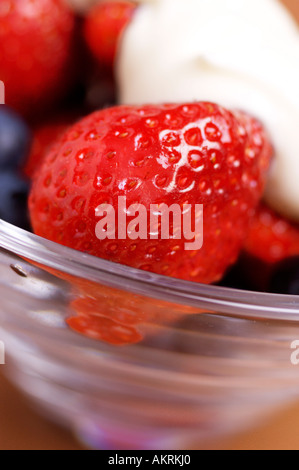 Close up de bol de fraises et de bleuets avec crème fraîche Banque D'Images