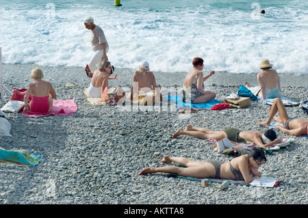 Nice, France scène de plage Mid Adult femmes bains de soleil près de l'océan dans les combinaisons de bain en vacances détente, vue arrière du groupe d'aînés Banque D'Images