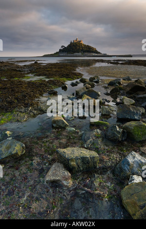 Les roches et flotsam menant à un soleil baigne le St Michael's Mount, Cornwall, Angleterre Banque D'Images