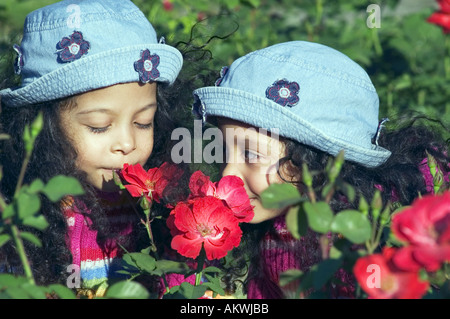 Deux sœurs jumelles qui sent les fleurs rouges Banque D'Images