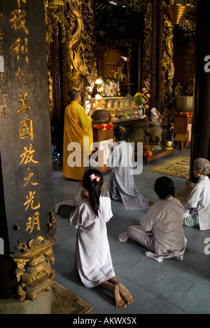 Les dévots s'agenouiller en prière avec moine au temple bouddhiste Pagode Vinh Trang à My Tho dans le Delta du Mékong du Vietnam Banque D'Images