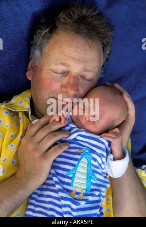 Heureux père dort avec bébé nouveau-né sur une couverture bleue Banque D'Images