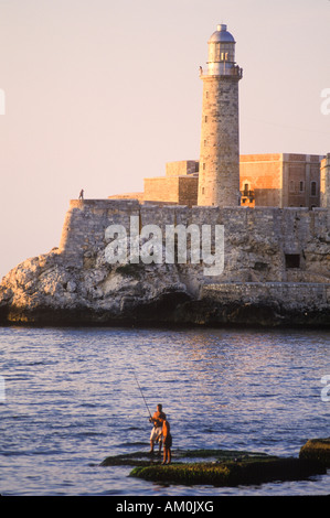 Les pêcheurs locaux le long de la célèbre Malecon au bord de l'eau, dans la vieille ville de La Havane avec la forteresse El Morro Banque D'Images