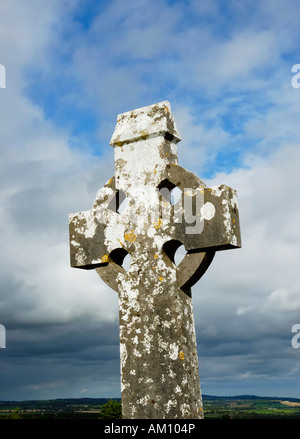 Croix en pierre typique de style celtique couverts par lichen gris en face de nuages douche atmosphérique Banque D'Images