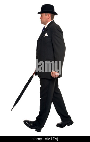 Ville d'affaires en costume rayé de l'axe portant un chapeau melon et portant un parapluie pendant qu'il marche le long de Banque D'Images