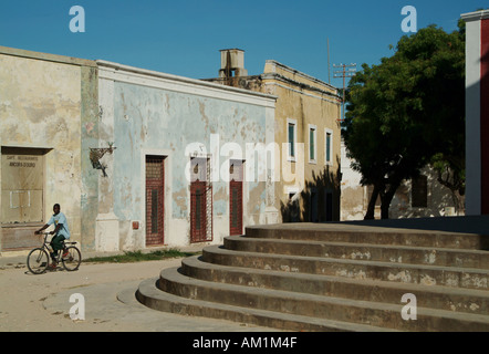 Un homme chevauche son vélo au-delà de l'architecture portugaise en ruine sur l'île de Ilha de Mozambique. Le Mozambique, l'Afrique du Sud Banque D'Images