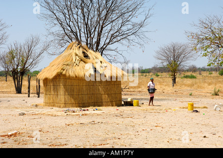 Femme près d'un toit de chaume typique hutte ronde d'Afrique, Botswana Banque D'Images