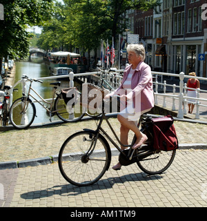 Woman riding a bicycle néerlandais noir traditionnel avec panier en osier. Les Pays-Bas l'Europe Banque D'Images