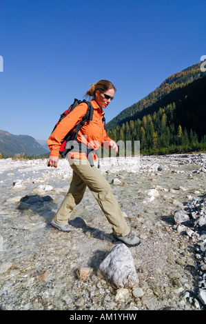 Femme randonnée traversant un ruisseau, Sextener Dolomites Tyrol du sud, Italie, Banque D'Images