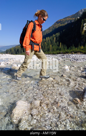 Femme randonnée traversant un ruisseau, Sextener Dolomites Tyrol du sud, Italie, Banque D'Images