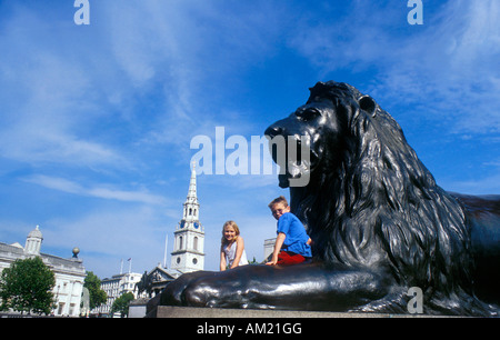 Des enfants assis sur un Lion à Trafalgar Square à Londres Banque D'Images