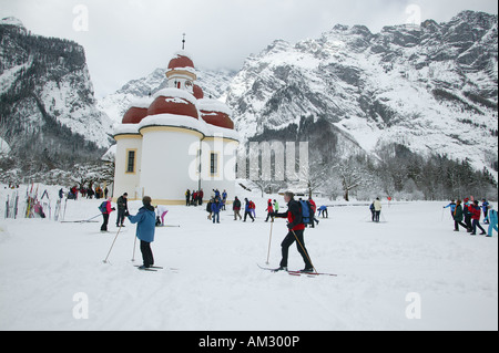 Église de Saint-Barthélemy à la Koenigssee congelé, les skieurs de fond, Berchtesgaden-campagne, Haute-Bavière, Allemagne Banque D'Images