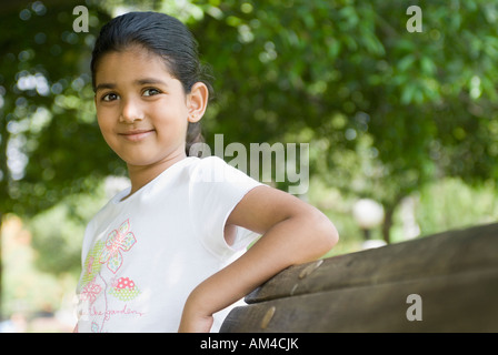 Girl appuyé contre un banc et souriant Banque D'Images