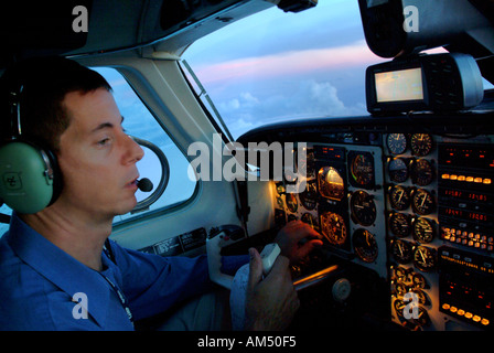 Pilote dans le cockpit d'un avion bimoteur turbopropulseur au crépuscule Banque D'Images