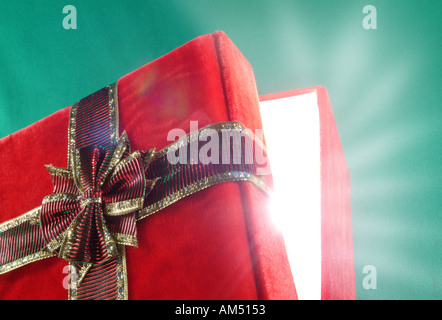 Boîte cadeau rouge avec couvercle ajar et rayons de lumière éclatant de Banque D'Images