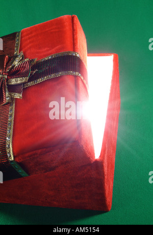 Boîte cadeau rouge avec couvercle ajar et rayons de lumière éclatant de Banque D'Images