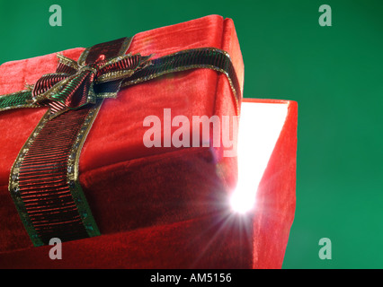Boîte cadeau rouge avec couvercle ajar et rayons de lumière éclatant de Banque D'Images