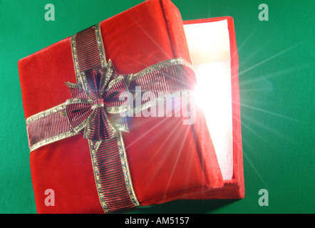 Boîte cadeau rouge avec couvercle ajar et rayons de lumière éclatant de Banque D'Images