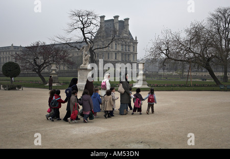 Un groupe de jeunes femmes musulmanes portant des burqas contre les enfants et de marcher à travers le jardin des Tuileries, Paris France Banque D'Images