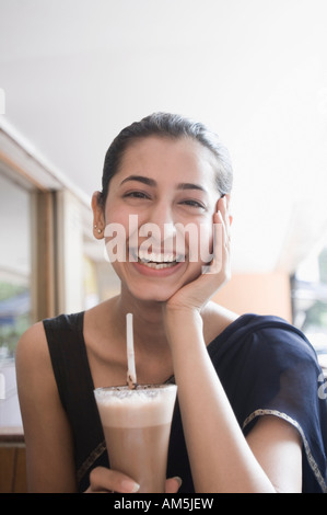 Portrait d'une jeune femme tenant un verre de lait aromatisé au chocolat et souriant Banque D'Images
