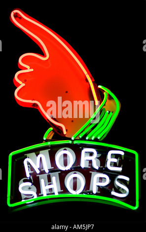 Plus de magasins enseigne au néon avec une main pointant vers la gauche et vers le haut. Fond noir Banque D'Images