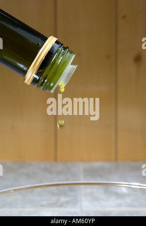 La dernière goutte d'huile d'olive depuis le col d'une bouteille verte Banque D'Images
