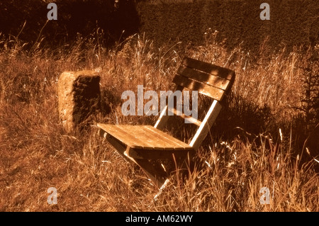 Image sépia d'un fauteuil de jardin en bois dans un jardin boisé. Banque D'Images