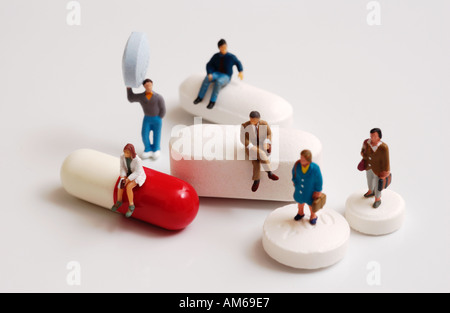 Groupe de petites figures debout sur assis sur et en maintenant une variété de comprimés et capsules Banque D'Images