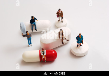 Groupe de petites figures debout sur assis sur et en maintenant une variété de comprimés et capsules Banque D'Images