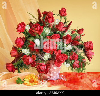 Studio organisé bouquet bouquet de roses rouges dans le panier sur un fond jaune pastel Banque D'Images