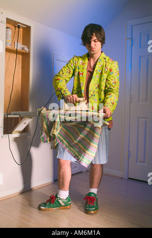 Nerdy boy wearing green jacket avec les personnages de dessins animés sur elle rayée chemise repassage Banque D'Images