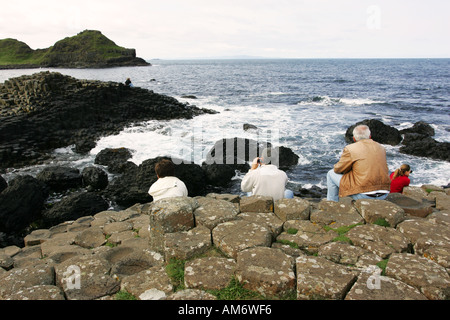 Les touristes s'asseoir et admirer le reste des formations de roche spectaculaires de la Chaussée des Géants, la Côte d'Antrim Irlande du Nord britannique NI GO Banque D'Images