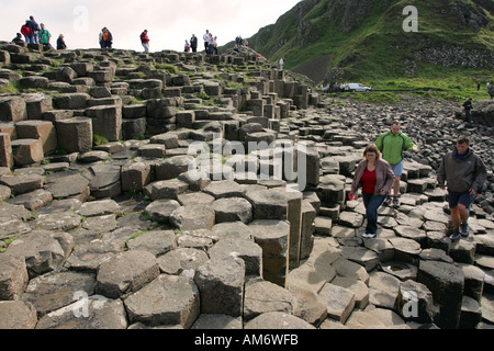 Les touristes à pied sur les spectaculaires rochers basaltiques hexagonales de la Chaussée des Géants, le comté d'Antrim Coast Irlande du Nord Royaume-uni de NI Banque D'Images