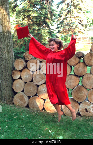 Femme diplômée à l'âge de 18 ans sauter de joie après la cérémonie de remise de diplômes. Elkhart Indiana USA Banque D'Images