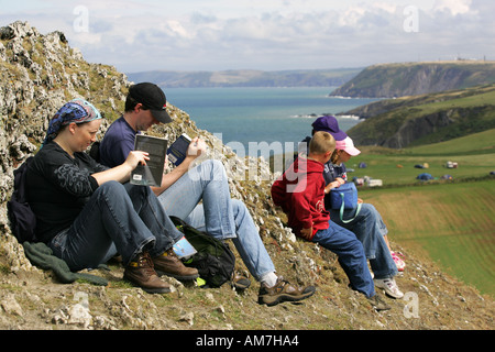 Les touristes randonneurs marcheurs reste sur la falaise au-dessus de Mwnt lire pique-nique travel guides maps Mid Wales Cardigan Bay sur la côte de la mer d'Irlande Banque D'Images