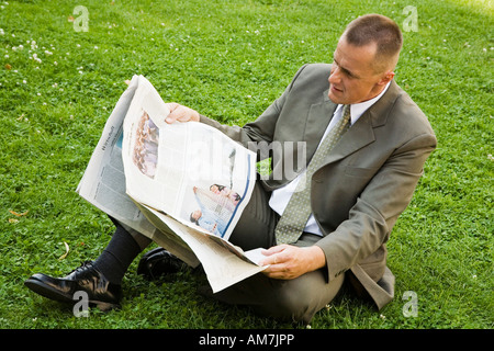 Businessman lit les pages d'un journal financier Banque D'Images