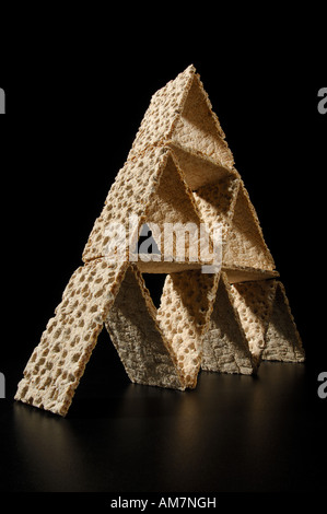 Pyramide de crispbreads empilés comme un château de cartes sur un fond noir Banque D'Images