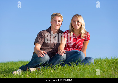 Un jeune couple assis sur un pré Banque D'Images
