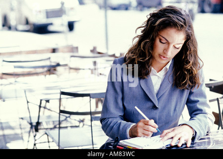 Young businesswoman writing in diary Banque D'Images