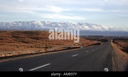 Route de campagne sur un plateau dans le Moyen Atlas, les montagnes du Haut Atlas derrière, Maroc Banque D'Images