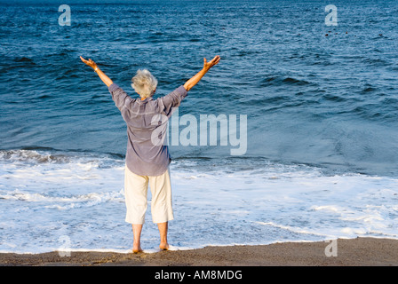Senior woman accueille une nouvelle journée à la plage Nauset Beach MA Cape Cod Banque D'Images