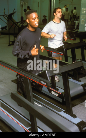 Deux hommes exerçant sur l'exécution de machines dans la salle de sport. Banque D'Images